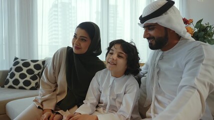 Arab family, father, mother, and son, pose together on a sofa in their modern living room, creating a heartwarming portrait of family unity - Powered by Adobe