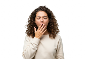 A young woman with curly dark hair, wearing a beige sweatshirt, yawning widely with her hand covering her mouth and eyes closed, isolated on white isolated on transparent background