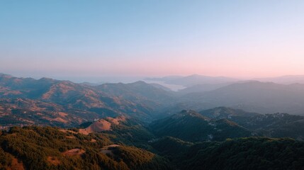 Fototapeta premium Serene Mountain Landscape at Dusk with Soft Pink and Orange Sky Overrolling Hills and Valleys