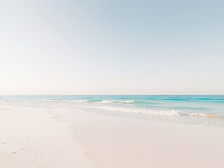 Obraz premium Serene coastal landscape showing the gentle waves washing onto the shore with soft light illuminating the tranquil beach