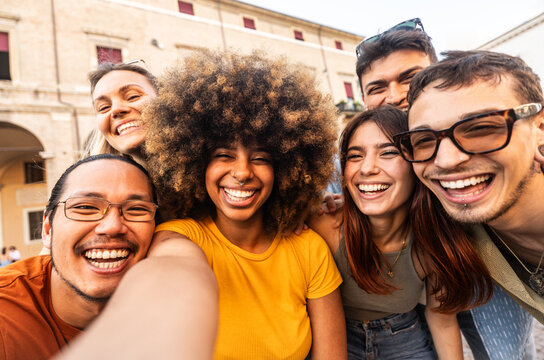 Multicultural cheerful friends taking selfie pic with smart mobile phone device - Youth community people laughing at camera together - Friendship concept with guys and girls having fun outdoors	