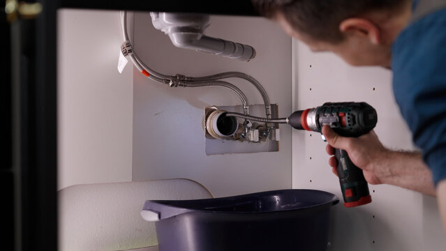 Plumber drill through clogged sink pipes with spring tube tool