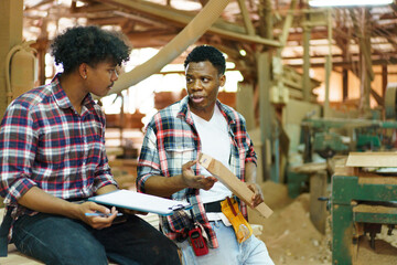 Two professional African carpenters are working together in sawmill or workshop.