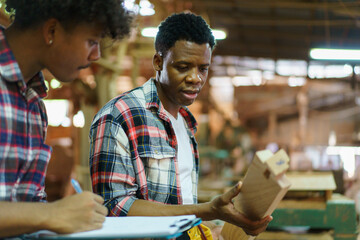Two professional African carpenters are working together in sawmill or workshop.