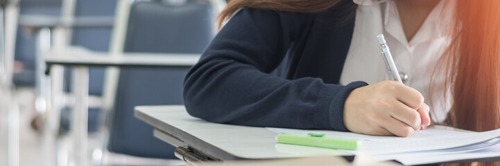 School exam student's taking educational admission test in class, thinking hard, writing answer in university classroom, education and world literacy day concept