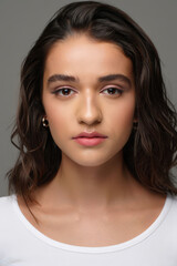 Fototapeta premium Portrait of a Beautiful Young Woman with Flawless Skin and Natural Makeup in a Studio Setting with a Neutral Gray Background for Beauty and Skincare Concepts