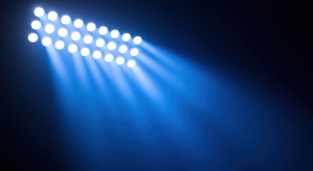 Obraz premium A cluster of bright stadium lights casts a wide, intense blue beam into the darkness