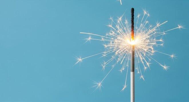 A single sparkler emitting bright light against a pastel azure background