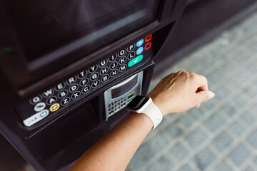 Person making contactless payment with smart watch to pay for parking. Paying at parking machine. Using NFC technology