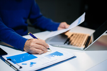 business documents on office desk with laptop and smart phone and graph business diagram and man...