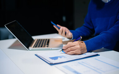 Fototapeta premium business documents on office desk with laptop and smart phone and graph business diagram and man working