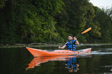 Kayaker paddling on calm lake amidst lush green forest