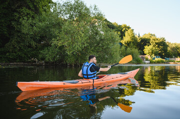 Kayaker paddling on calm lake in summer sunset light