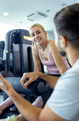 Mid adult woman and personal fitness trainer having conversation during workout at gym.