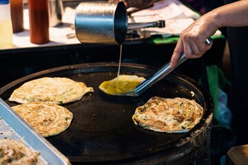 Anonymous Street food vendor preparing delicious roti canai on hot griddle