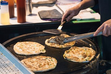 Anonymous Street vendor cooking delicious scallion pancakes on hot griddle