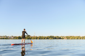 Sportsman paddling on sup board on lake during summer day