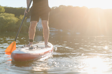 Sportsman paddling on sup board at sunset on lake
