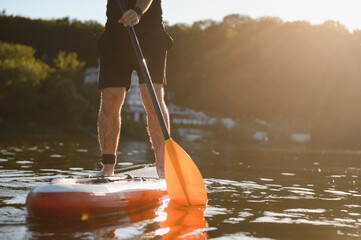 Sportsman paddling on sup board at sunset on lake