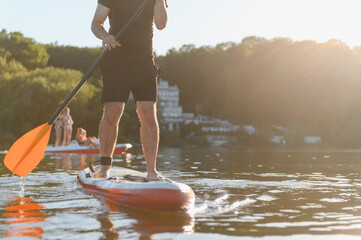 Man paddling on sup board at sunset on a lake