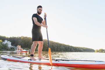 Sportsman paddling on sup board at sunset on a lake