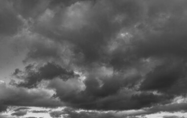 Moody monochrome image showing a sky filled with heavy storm clouds over a distant horizon