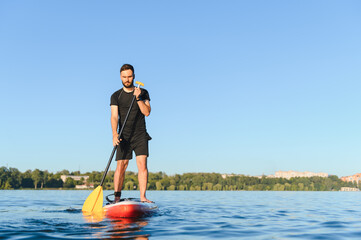 Sportsman paddling on sup board on lake in summer