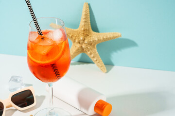 Summer alcohol cocktail drink at blue background. Aperol Spritz in wine glass and sunglasses,...