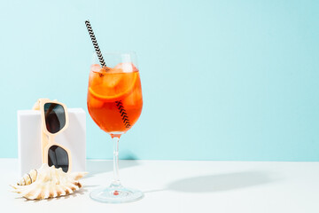 Summer alcohol cocktail drink at blue background. Aperol Spritz in wine glass and sunglasses,...