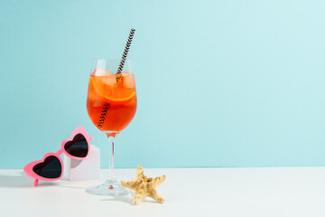 Summer alcohol cocktail drink at blue background. Aperol Spritz in wine glass and sunglasses,...