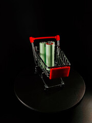 Mini shopping cart displays green rolls on a dark background during a studio setup