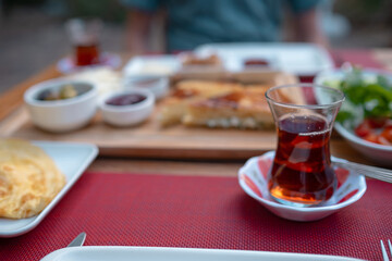 Traditional Turkish breakfast spread with fresh bread, olives, cheese, tomatoes, cucumbers, and variety of jams and spreads. Enjoyed in vibrant setting, capturing essence of Turkish morning culture.