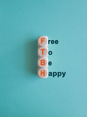 FTBH Free To Be Happy symbol. Concept word FTBH Free To Be Happy on wooden cubes. Beautiful blue...