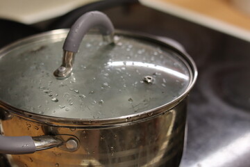 Steam gathers on the lid of a pot while cooking on a stovetop in a cozy kitchen setting