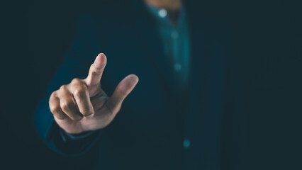 A person in a dark outfit touches an invisible digital interface with their index finger.