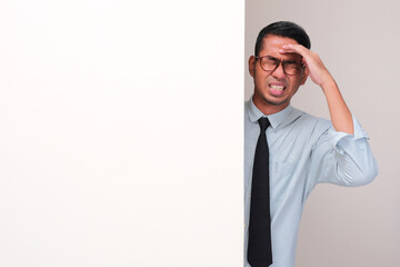 An employee peeking behind a wall suffering bad headache