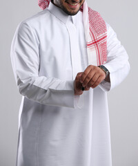 saudi arabian man in thob standing with wearing wrist watch in hand