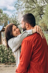Obraz premium Multiracial husband lifts wife playfully in his arms outdoors. They share a joyful, loving moment full of fun, affection, and strong connection, celebrating diversity and togetherness.