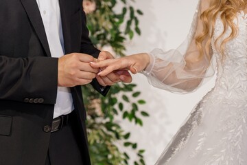 Romantic Wedding Ceremony Exchange: Groom Placing Ring on Bride's Finger Amidst Floral Decoration,...