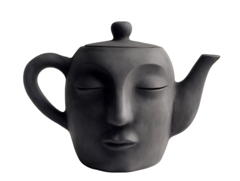Black ceramic teapot shaped like a face with closed eyes on transparent background
