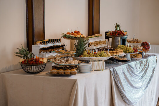 Elegant Banquet Table Display with Assorted Appetizers, Fruit Platters and Decorative Elements in a Warm Lit Interior Setting.
