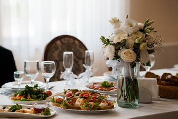 Elegant Wedding Table Setting with White Floral Arrangement, Fine Dining Plates, and Champagne Glasses, Soft Light, Romantic Celebration Scene