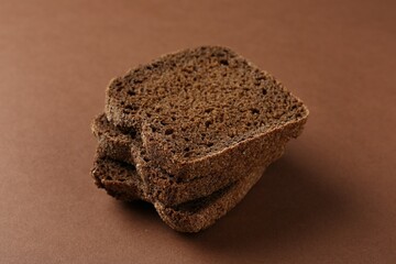 Pieces of fresh rye bread on brown background, closeup