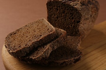 Pieces of fresh rye bread on brown background, closeup
