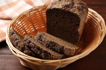 Pieces of fresh rye bread in wicker basket on wooden table, closeup