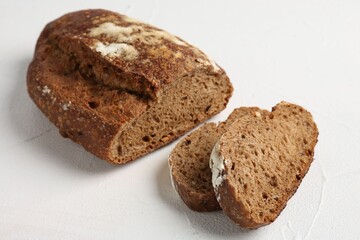Pieces of fresh rye bread on white textured table, closeup