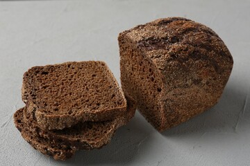 Pieces of fresh rye bread on light grey textured table, closeup