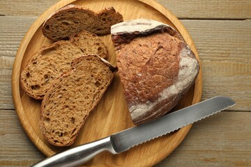 Pieces of fresh bread and knife on wooden table, top view