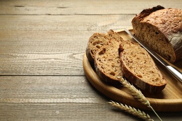 Pieces of fresh bread, spikes and knife on wooden table, closeup. Space for text