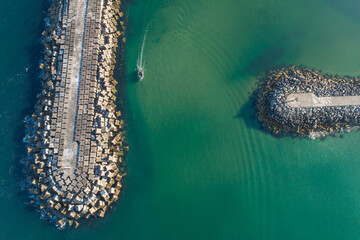 Obraz premium Commercial and Recreational Boating Hub Aerial View of a Stone Jetty Extending into Green Sea, aerial drone top down view
